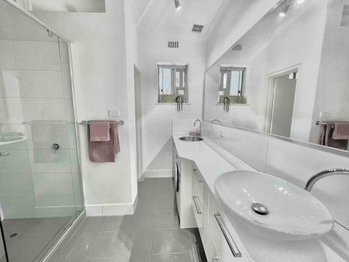 a white bathroom with a sink and a shower at 2 Minute walk from the Waters Edge in Perth