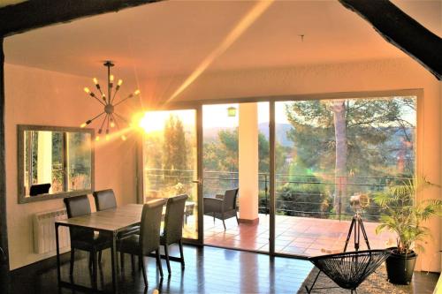 een eetkamer met een tafel en stoelen en een groot raam bij Villa Wanderlust Sitges Hills. Exclusive pool. in Olivella