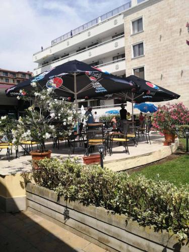 a group of tables and chairs with an umbrella at Aparthotel Hotel Prestige City II in Primorsko