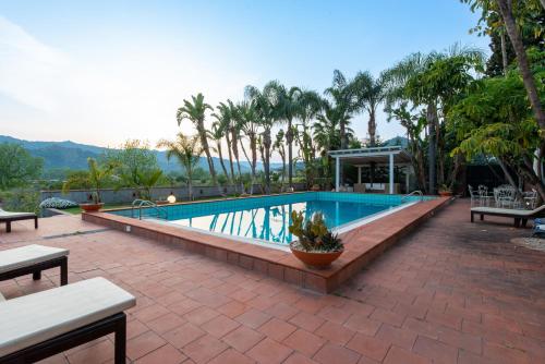 una piscina con bancos y palmeras en Villa with pool & jacuzzi, en Taormina