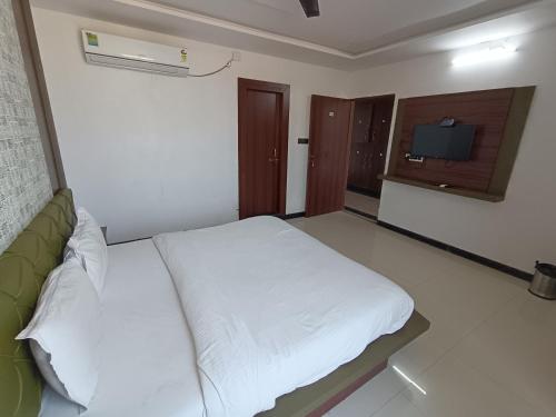 a bedroom with a white bed and a television at Hotel LAAKHAN BY GHUMO UDAIPUR in Udaipur