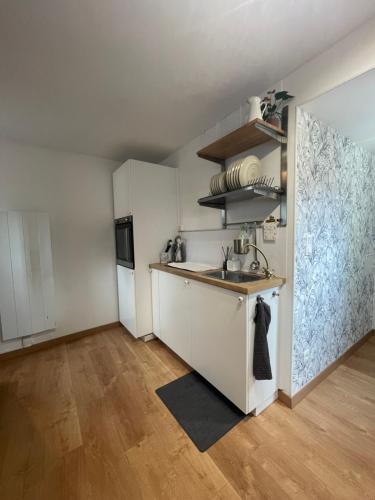 Elle comprend une petite cuisine avec des placards blancs et un évier. dans l'établissement Petit maison avec terrasse proche de Rouen 1h30 de Paris, à Bihorel