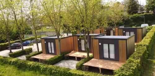 eine Reihe kleiner Häuser in einem Park mit Bänken in der Unterkunft CAMP'HOTEL in Mamers