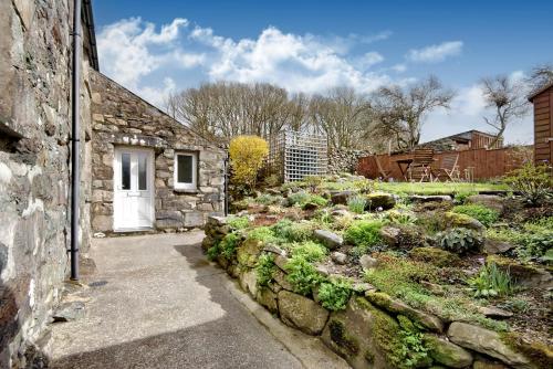 a stone house with a stone wall and a garden at Ty Capel Jeriwsalem in Trawsfynydd