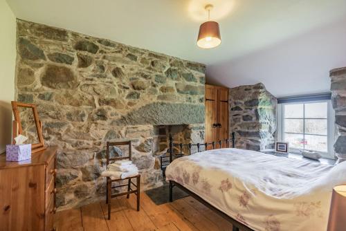 ein Schlafzimmer mit einer Steinmauer und einem Bett in der Unterkunft Ty Capel Jeriwsalem in Trawsfynydd