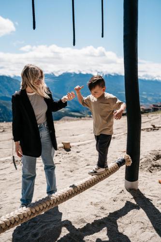 a woman and a boy standing on a rope bridge at Familienhotel Familiamus in Maranza
