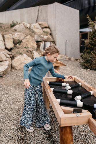 a young girl playing with a table with white balls at Familienhotel Familiamus in Maranza