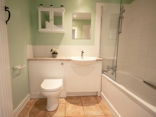 a bathroom with a toilet and a sink and a tub at Corner Cottage in Shaftesbury