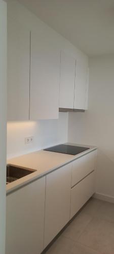 a white kitchen with white cabinets and a sink at Alpha 503 in De Panne