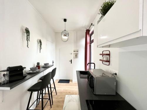 une cuisine avec des murs blancs et un comptoir avec des tabourets dans l'établissement Le JOY, studio au coeur de la ville, à Beauvais