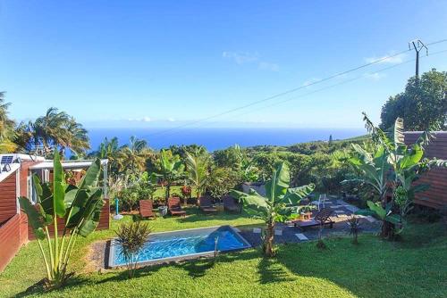 Elle offre une vue sur une cour avec une piscine et l'océan. dans l'établissement L’escapade créole jacuzzi privatif Bungalow Ananas, à Saint-Joseph
