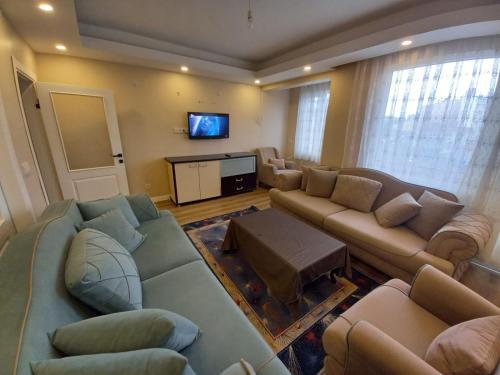 a living room with couches and a flat screen tv at Dilmac Hotel in Gelibolu