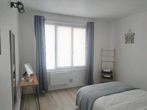 a bedroom with a bed and a large window at Charmant logement à 2 pas de la plage in Le Portel