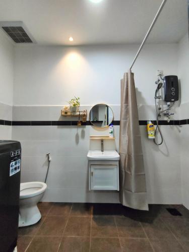 een badkamer met een toilet, een wastafel en een spiegel bij DH Merlimau Homestay in Merlimau