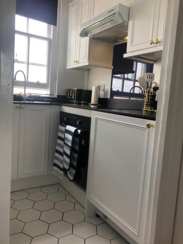 uma cozinha com armários brancos e um forno com placa de fogão em SEAFRONT SANCTUARY Beautiful Art Deco Apartment with Stunning City & Sea Views em Brighton & Hove