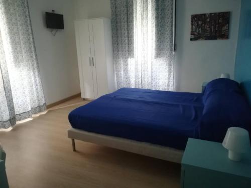 a bedroom with a bed with blue sheets and windows at Barnet House Lamezia in Lamezia Terme