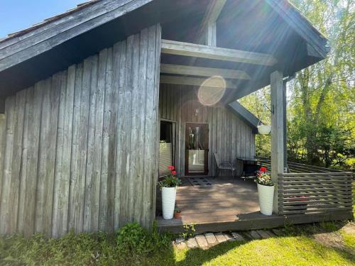 a wooden house with two vases of flowers on a porch at Sea Side house (70m2) Lejas Ziediņi in Plieņciems