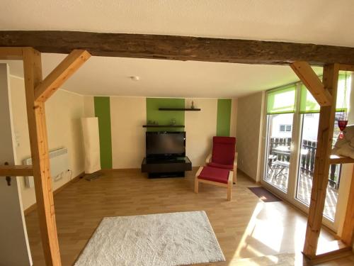 a living room with a television and a red chair at Ferienhaus Hoher Meißner in Germerode