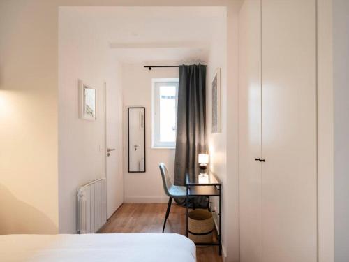 Un dormitorio con una cama y un escritorio y una ventana. en Le Coquet des Trois-Maisons avec parking privatif, en Nancy