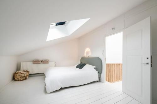 a white bedroom with a bed and a skylight at The Sebastian in Antwerp