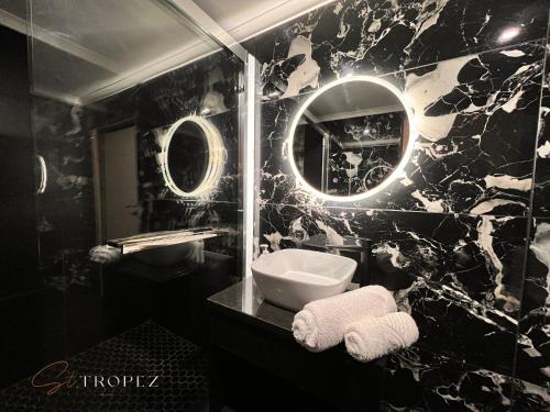 a black and white bathroom with a sink and a mirror at St Tropez Guest House in Phuthaditjhaba