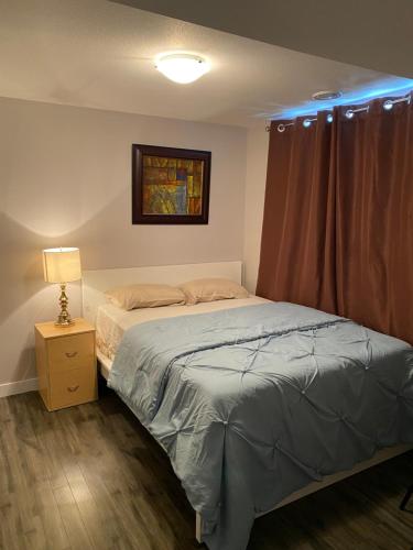 1 dormitorio con cama y mesita de noche con lámpara en A cozy 1 bedroom suit en Saskatoon