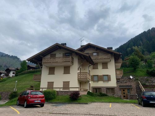 a large building with cars parked in a parking lot at Appartamento Genziana in Predazzo