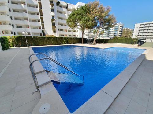 a swimming pool with a bench in front of a building at 5 Salou,Playa,Piscina cento PARKING in Salou