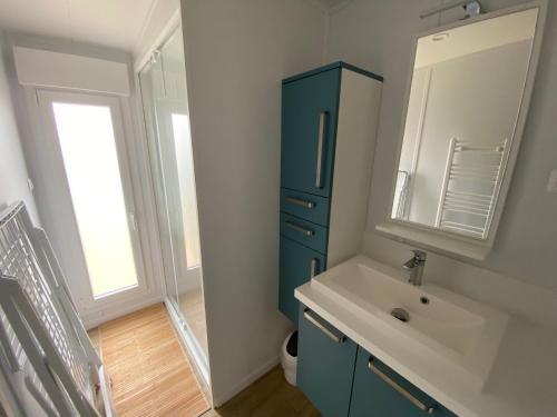 La salle de bains est pourvue d'une armoire bleue et d'un lavabo. dans l'établissement Cottage moderne en bord de mer, à Bretignolles-sur-Mer
