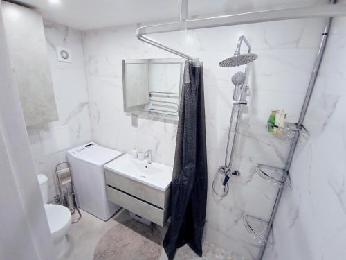 a white bathroom with a sink and a shower at Miesto šviesų apartamentai Telšiuose in Telšiai