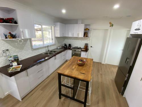 a kitchen with white cabinets and a wooden table at Preston Valley Country Cabin in Lowden
