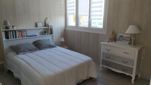 - une chambre avec un lit blanc et une étagère dans l'établissement Les Becs - Appartement bord de mer, 1 chambre, à Saint-Hilaire-de-Riez