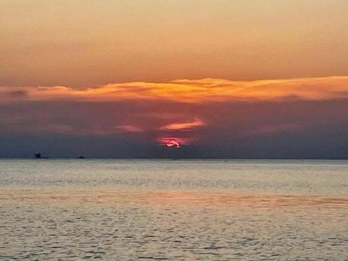 a sunset over the ocean with a cloudy sky at Bungalow on the beach (C6) in Thongsala