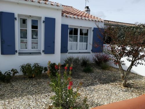 una casa con puertas azules y flores delante de ella en nataliledeco bed and breakfeast en La Guérinière
