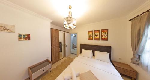 a bedroom with a white bed and a chandelier at Castello Marmaris Holiday Home in Marmaris