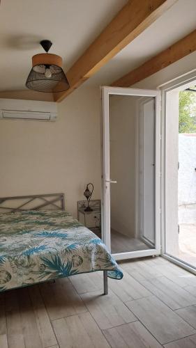 1 dormitorio con 1 cama y puerta corredera de cristal en STUDIO MILHAUD en Milhaud