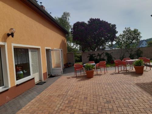 un patio avec des chaises et des tables rouges et un bâtiment dans l'établissement Bed and Breakfast 2, à Korswandt