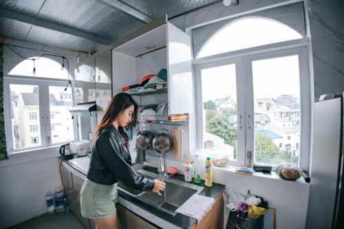 a woman standing in a kitchen with a sink at Hotel Thanh Nhung in Da Lat