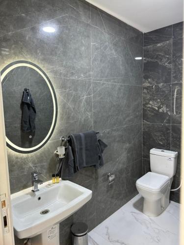 La salle de bains est pourvue d'un lavabo, de toilettes et d'un miroir. dans l'établissement Bella Address Hotel Beach, à Saïdia