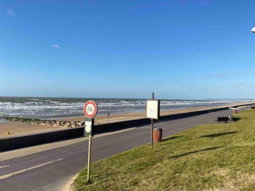 a road next to a beach with the ocean at L'échappée Cabourgeaise in Cabourg