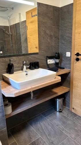 a bathroom with a white sink and a mirror at Ferienwohnungen LODGE-B in Weissenbach am Lech