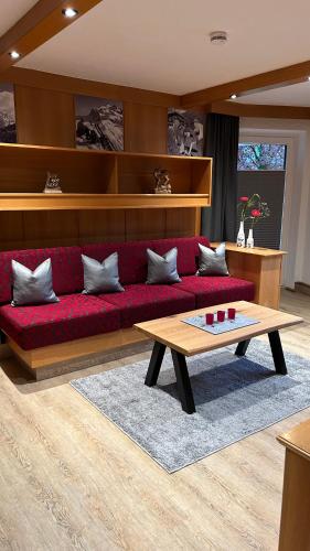 a living room with a red couch and a table at Ferienwohnungen LODGE-B in Weissenbach am Lech