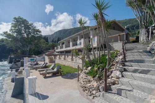 a house on the side of a river with palm trees at Thomas Beach Studios in Paleokastritsa