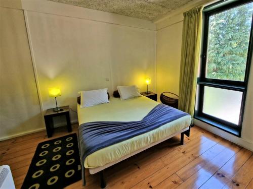 a bedroom with a bed and a large window at HI Geres - Pousada de Juventude do Gerês in Geres