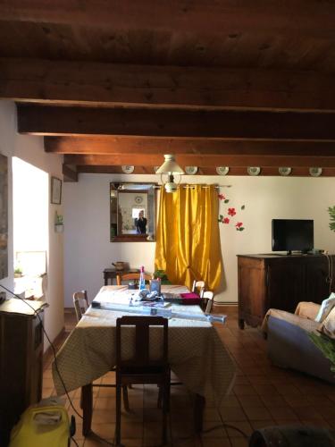 a living room with a table and yellow curtains at Détente en campagne dans le quercy une Chambre lit double et un matelas d appoint une personne dans le salon in Castelnau-de-Montratier