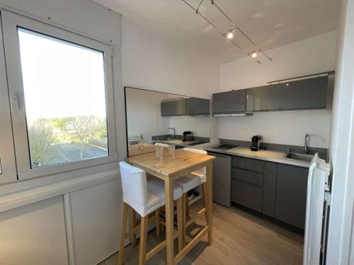 une cuisine avec une table en bois et une grande fenêtre dans l'établissement Studio rénové 2 pers avec parking, wifi, proche plage - FR-1-224C-28, à Saint-Jean-de-Monts