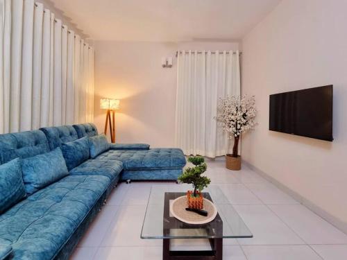 a living room with a blue couch and a tv at Dianella Inn in Dhaka