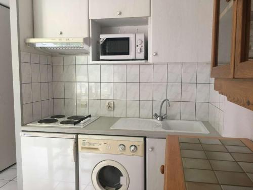une cuisine avec un lave-linge et un micro-ondes dans l'établissement Studio cabine 4 pers, balcon sud, parking, prox centre Luz-St-Sauveur, proche ski et thermes - FR-1-402-72, à Luz-Saint-Sauveur