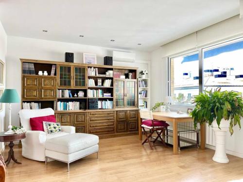 ein Wohnzimmer mit einem Schreibtisch, einem Stuhl und einem Tisch in der Unterkunft Moderno y amplio apartamento en el centro de Roses in Roses