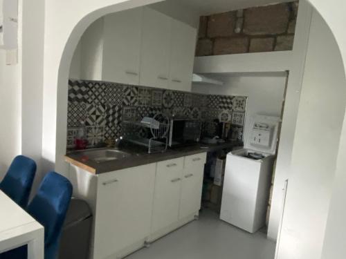 een keuken met witte kasten, een wastafel en een koelkast bij Logement T2 terrasse vue sur piscine in Larche